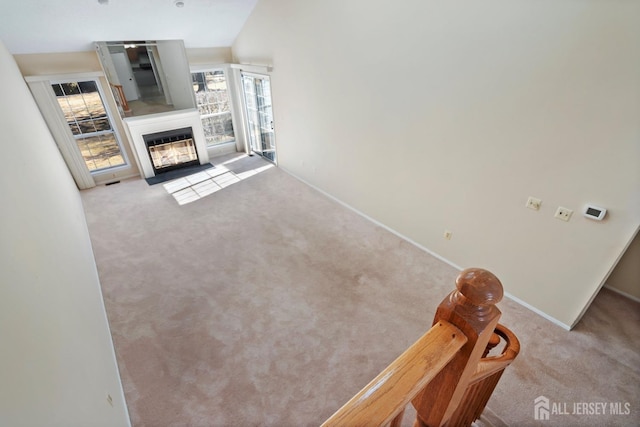 carpeted living room featuring baseboards and a fireplace with flush hearth