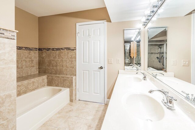 bathroom featuring double vanity, a garden tub, a tile shower, and a sink