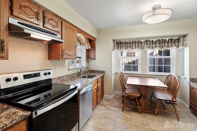 kitchen with appliances with stainless steel finishes, light tile patterned flooring, sink, and dark stone counters