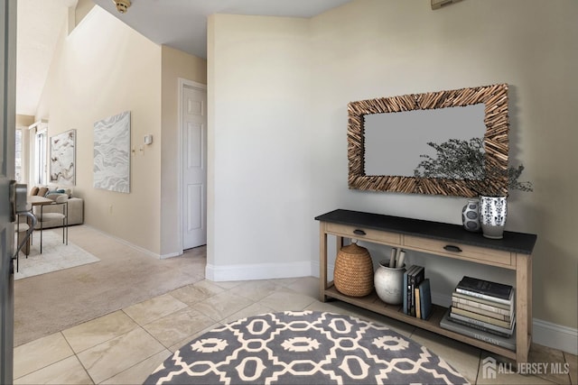 hallway featuring tile patterned floors, carpet, and baseboards
