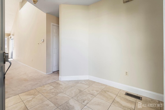 spare room with light colored carpet, visible vents, baseboards, and light tile patterned flooring