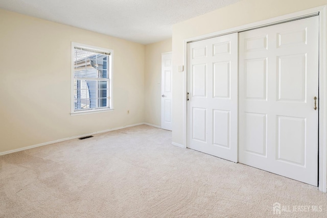 unfurnished bedroom with light carpet, a closet, and a textured ceiling