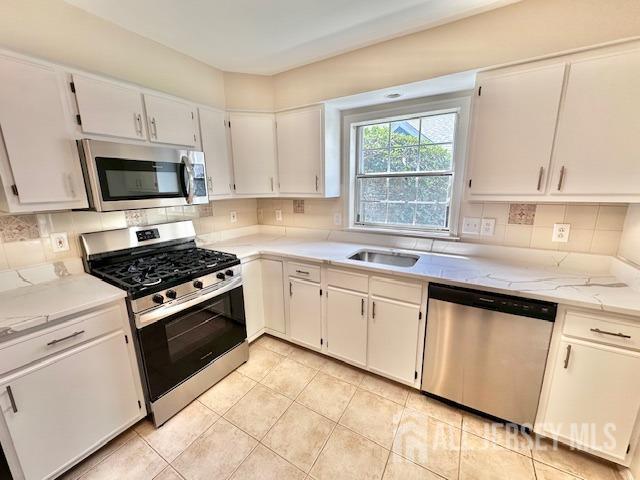 13-B Ashbourne Dr Unit B, Monroe, NJ 08831 - kitchen featuring appliances with stainless steel finishes, light countertops, decorative backsplash, light tile patterned floors, and white cabinets