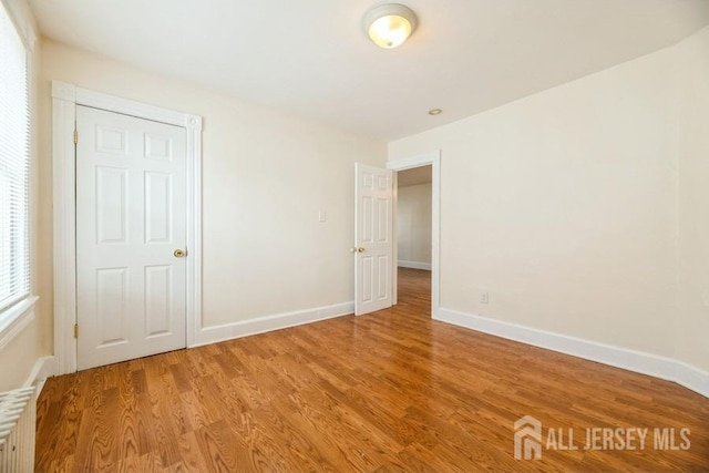 251 Henry St, South Amboy, NJ 08879 - unfurnished bedroom featuring radiator, light wood-style floors, and baseboards