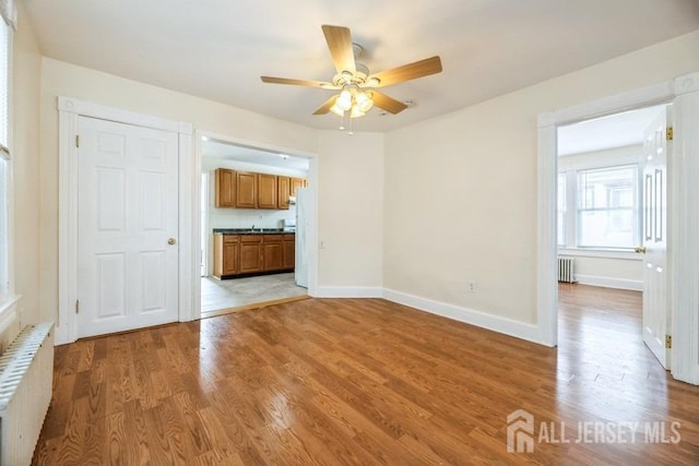 251 Henry St, South Amboy, NJ 08879 - empty room with radiator heating unit, a ceiling fan, light wood-style flooring, and baseboards