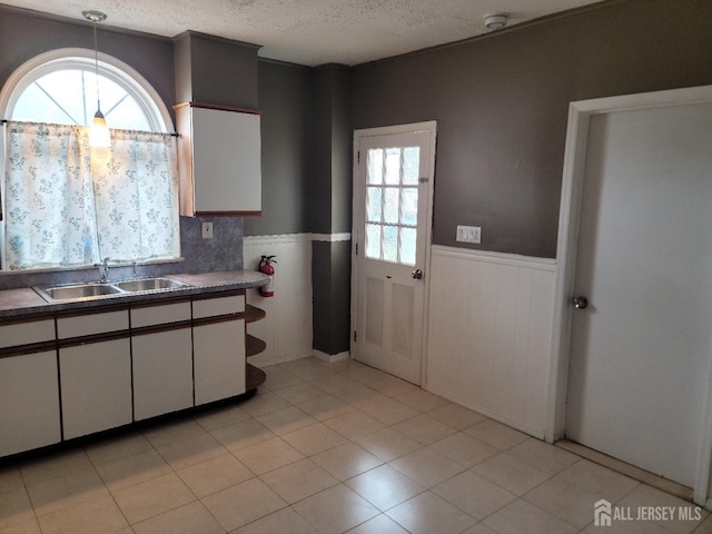 251 Henry St, South Amboy, NJ 08879 - kitchen with wainscoting, a sink, plenty of natural light, white cabinetry, and a textured ceiling