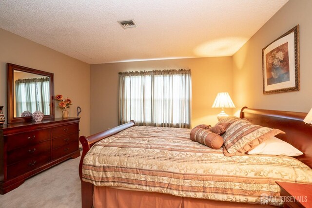 bedroom with light carpet and a textured ceiling