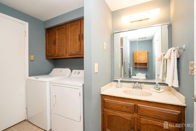 clothes washing area with cabinets, washer and clothes dryer, and sink