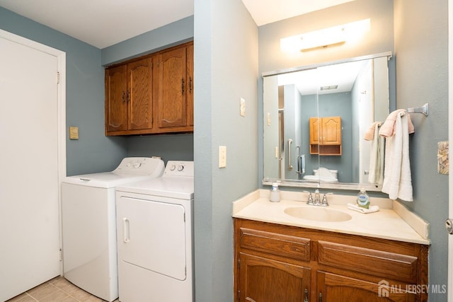 washroom featuring washing machine and dryer, cabinet space, and a sink