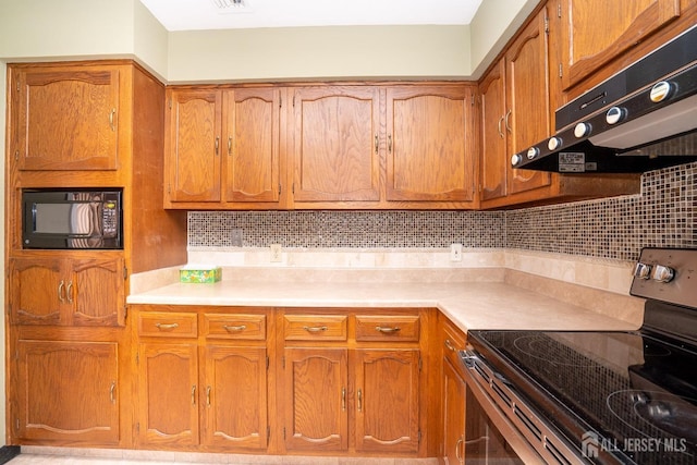 kitchen featuring black microwave, electric stove, light countertops, and under cabinet range hood