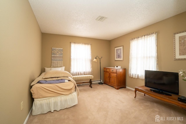 bedroom featuring a baseboard heating unit, light carpet, and a textured ceiling