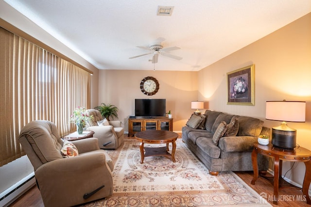 living room with a baseboard heating unit, hardwood / wood-style flooring, and ceiling fan