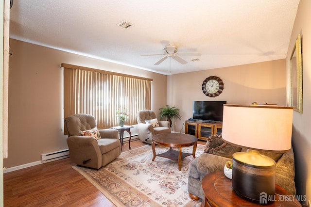 living room featuring hardwood / wood-style floors, a textured ceiling, ceiling fan, and baseboard heating