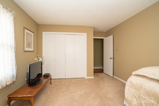 carpeted bedroom featuring a closet, a textured ceiling, and baseboard heating