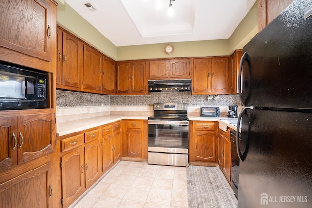 kitchen featuring backsplash, black appliances, and a raised ceiling