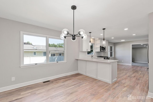 141 Day St, South Plainfield, NJ 07080 - kitchen with light wood-type flooring, baseboards, light countertops, a chandelier, and a sink