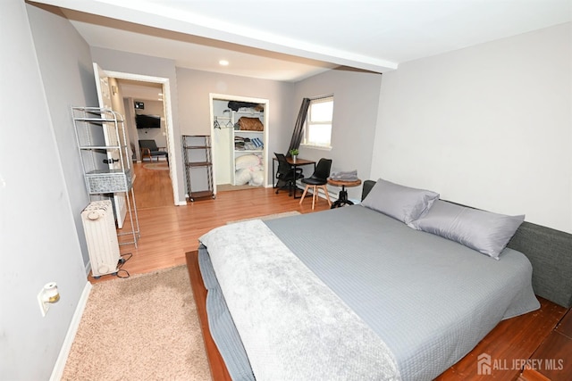 bedroom featuring radiator heating unit, baseboards, and wood finished floors