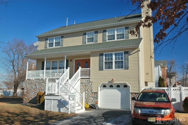 view of front of house featuring an attached garage, covered porch, fence, stairs, and a chimney