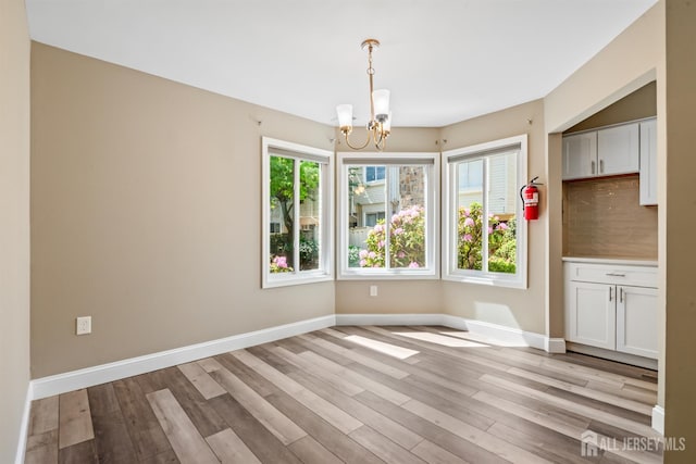 1018 Schmidt Ln, North Brunswick, NJ 08902 - unfurnished dining area with a chandelier, light wood finished floors, and baseboards
