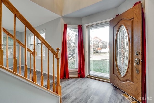 entryway with stairway, visible vents, baseboards, and wood finished floors