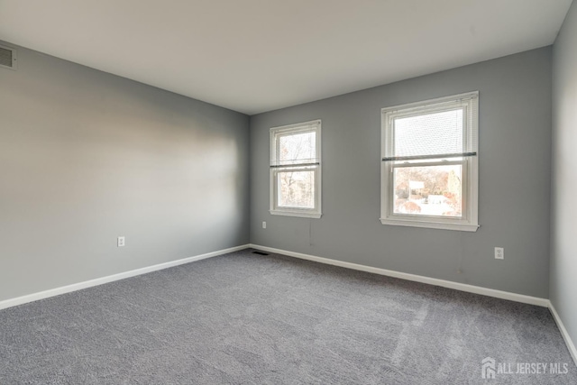 empty room with visible vents, baseboards, and carpet