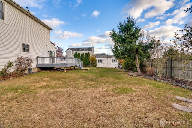 view of yard featuring an outdoor structure, a deck, and fence