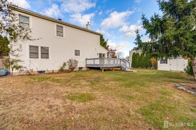 back of house with a lawn, a chimney, and a deck