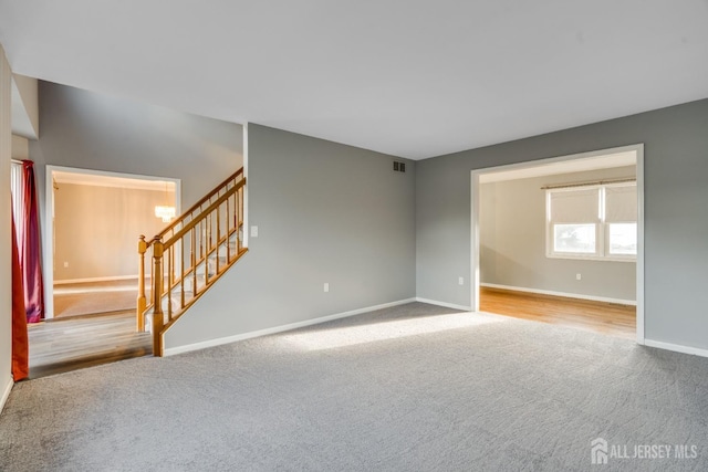 unfurnished room featuring baseboards, stairway, carpet floors, and visible vents