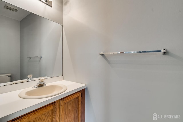 half bathroom with vanity, toilet, and visible vents