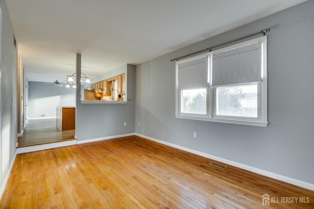 empty room with a ceiling fan, visible vents, light wood-style floors, and baseboards