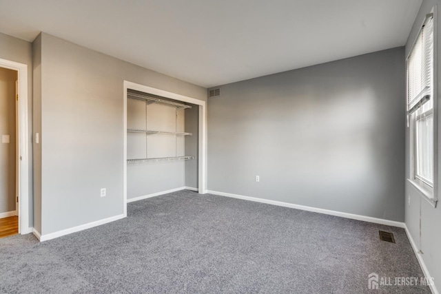 unfurnished bedroom featuring multiple windows, visible vents, and carpet floors