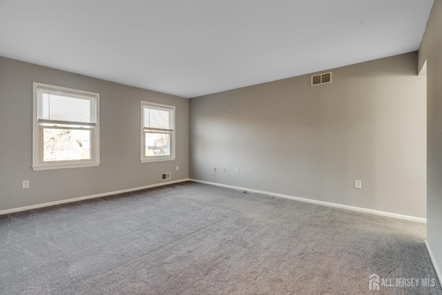 carpeted spare room featuring visible vents and baseboards