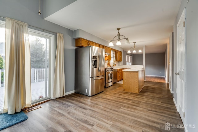 kitchen with visible vents, light countertops, brown cabinets, appliances with stainless steel finishes, and wood finished floors