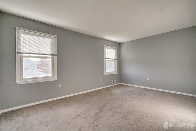 carpeted spare room featuring visible vents and baseboards