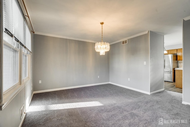 carpeted empty room with visible vents, baseboards, an inviting chandelier, and crown molding