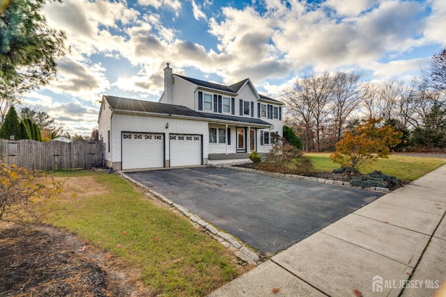 view of front facade featuring fence, an attached garage, a chimney, a front lawn, and aphalt driveway