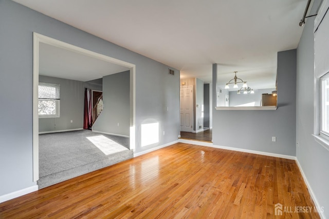 empty room featuring stairway, visible vents, baseboards, and wood finished floors