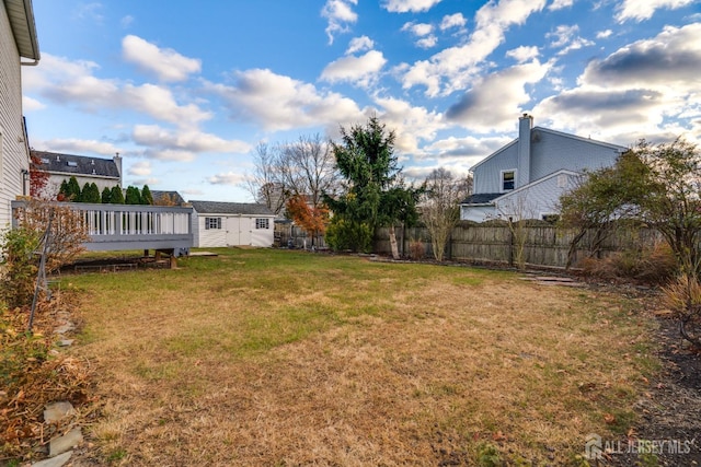 view of yard with a deck, an outdoor structure, fence, and a storage shed