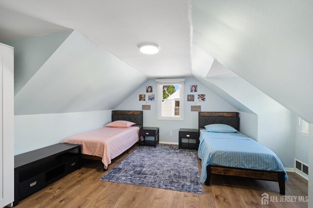 bedroom featuring baseboards, lofted ceiling, wood finished floors, and visible vents