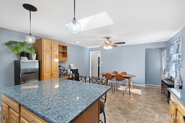 553 Harrison Ave, South Plainfield, NJ 07080 - kitchen featuring freestanding refrigerator, ceiling fan, a kitchen island, a skylight, and dark stone counters