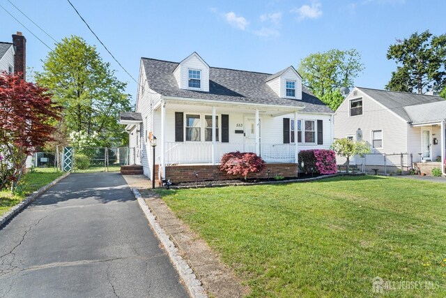 cape cod home with a porch, a front yard, fence, and roof with shingles