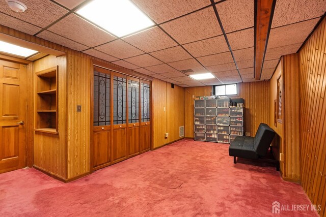 unfurnished room with carpet floors, wood walls, built in features, and visible vents
