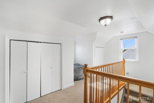 interior space with light colored carpet, an upstairs landing, and lofted ceiling