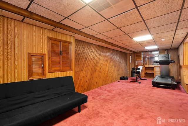 exercise room featuring wood walls, a paneled ceiling, and carpet flooring