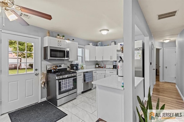 60 Sycamore St, Carteret, NJ 07008 - kitchen featuring stainless steel appliances, light countertops, white cabinets, a ceiling fan, and backsplash