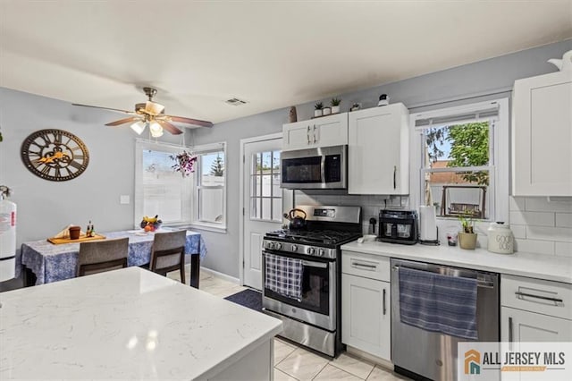 60 Sycamore St, Carteret, NJ 07008 - kitchen with appliances with stainless steel finishes, backsplash, a ceiling fan, white cabinetry, and light stone counters