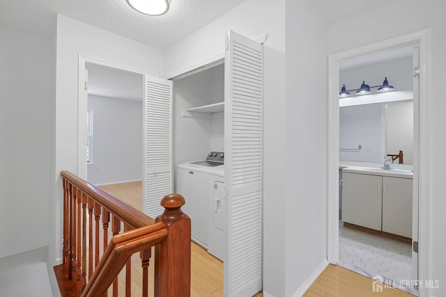 18 Albury Way N, Brunswick, NJ 08902 - hallway with washer / dryer, an upstairs landing, light wood-style flooring, a textured ceiling, and a sink