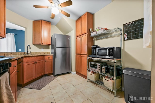 kitchen featuring sink, light tile patterned floors, ceiling fan, appliances with stainless steel finishes, and light stone counters