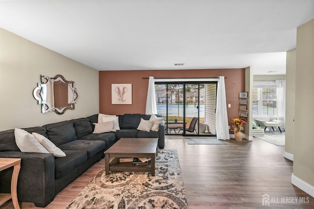 living area with visible vents, baseboards, and wood finished floors