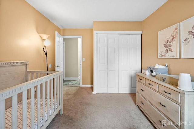 bedroom featuring a nursery area, light colored carpet, and a closet